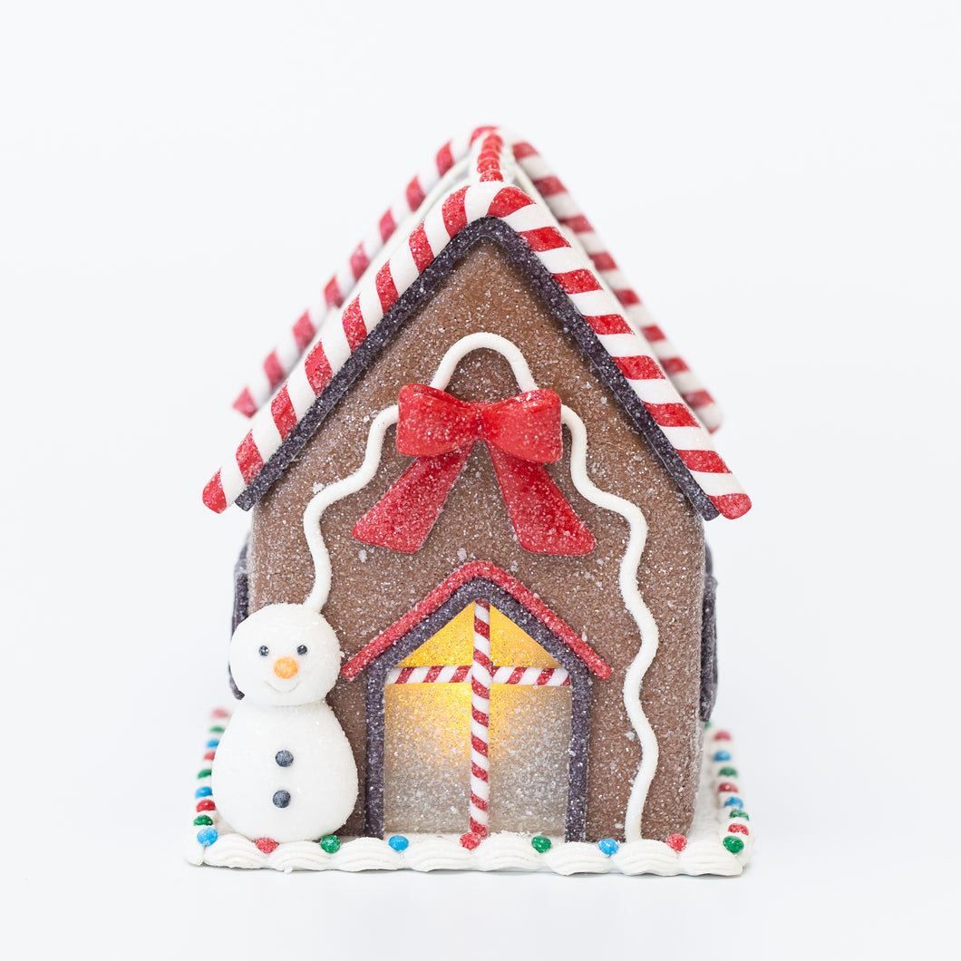 Pre-lit gingerbread house with a snowman and a bow